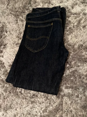 Lee Jeans | Daren zip fly - Snygga mörkblå jeans med klassisk femficksdesign och kontrastsömmar. Raka ben och normal passform, perfekta för en chill och stilren look. Materialet är slitstarkt jeans och färgen är djupblå med gul söm. Passar dig som gillar enkel och tidlös stil. Jeansen är använda minimalt och har inga tecken på användning. 