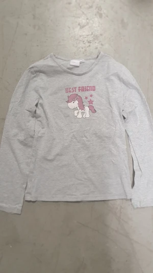 Tröja - Supersöt grå långärmad tröja från mywear young med tryck av en enhörning och texten 'BEST FRIEND' i rosa. Tröjan har rund hals och är gjord i mjuk bomull, perfekt för dig som gillar gulliga motiv och vill ha något bekvämt till vardagen.