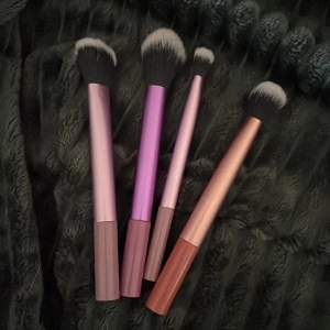 Set med fyra sminkborstar i pastell.  - Fyra snygga sminkborstar med metalliska skaft i rosa, lila och kopparfärg, ej använda. Borstarna har mjuka syntetiska borst i svart och vitt, perfekta för applicering av puder, rouge eller highlighter. Passar både till ansikte och detaljerad makeup. Säljs som set eller enskilt.