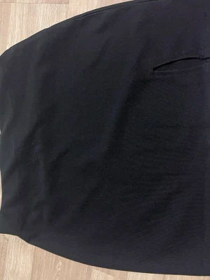 Svart pennkjol från B. B. Sister - Klassisk svart pennkjol från B. B. Sister i storlek L. Kjolen har en stilren design med diskret fickdetalj framtill och är tillverkad i ett mjukt, stretchigt material som sitter snyggt. Perfekt för dig som gillar en enkel och tidlös look.