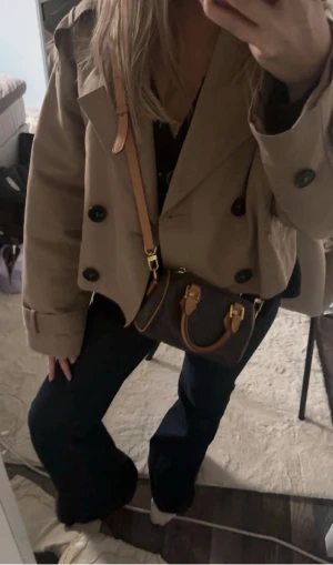 Louis Vuitton Mini Monogram Handväska - Säljer en ikonisk handväska från Louis Vuitton i klassiskt brunt monogrammönster. Väskan har rund form, två korta handtag i ljust skinn och guldfärgade metalldetaljer. Lite av guldfärgen har tyvärr nöts bort från dragkedjan och vissa delar men inget som märks. Det är en Nano Speedy med ett axelband. Jag köpte den från Sellpy innan för 6000kr därför säljer jag den för 4600 men pris går att diskutera.