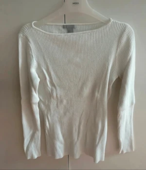 Vit ribbad långärmad tröja H&M - Säljer en vit långärmad tröja från H&M. Tröjan har ett ribbat mönster och är figurnära med rund halsringning. Perfekt att styla med jeans eller kjol. Tyvärr har tröjan ett par små svarta prickar framtill