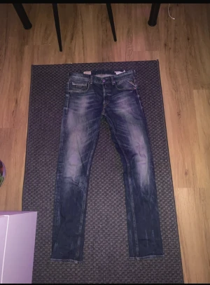 Replay Grover jeans blå herr - Säljer ett par Replay Grover jeans i klassisk blå tvätt med snygga slitningar och raka ben. Jeansen har fem fickor, normal passform och tydliga Replay-detaljer på fickan och bak. Perfekta för dig som gillar en tidlös och avslappnad stil.