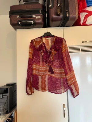 Cream blus  - Säljer en otroligt vacker vinröd, orange och beige blus. Den är något transparent. Från märket Cream i storlek 40. Mycket fint skick, jag hittar inga synliga anmärkningar eller defekter. 