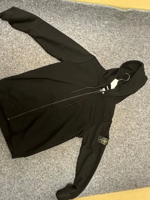 Stone Island, zip hoodie. - Svart zip hoodie från stone island. Klassiska patch loggan på vänster arm. Tröjan är oanvänd, leveras i originalförpackning. 