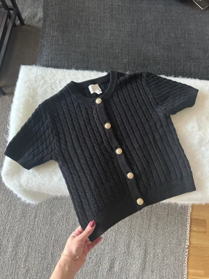 Svart kabelstickad tröja med guldknappar - Svart kabelstickad tröja med guldknappar. Använd sparsamt och i fint skick! 