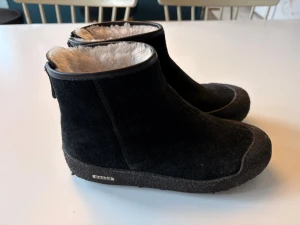Svarta Bally boots med fårskinn - Boots från Bally i svart mocka med mjukt vitt fårskinnsfoder. Modellen har rund tå och platt sula, perfekt för kalla dagar. Diskret Bally-logga på sidan och robust yttersula för extra grepp. Snygg och enkel design som håller dig varm hela vintern. Knappt använda. Modellen heter Bally Guard II. Kallas curlingkjängor.  Säljer pga för små.  (Jag har 38,5 egentligen).