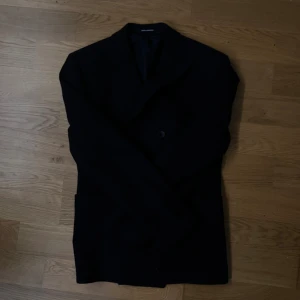 Svart kavaj Pinolerario 46/8R - Stilren svart kavaj från Pinolerario i klassisk modell med två knappar framtill och snygg passform. Perfekt för dig som vill ha en tidlös look. Storlek 46/8R. Fodrad insida och diskreta fickor. Snygg att matcha med skjorta eller t-shirt.