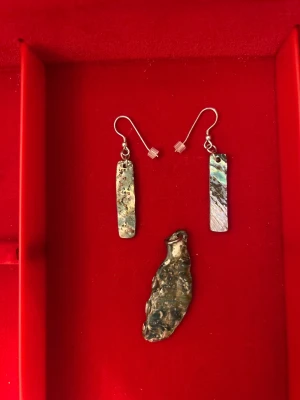 Unika örhängen och hänge i äkta silver - Säljer ett par örhängen med rektangulära hängen i äkta silver och pärlemor, samt ett matchande organiskt format hänge. Örhängena har krokfästen och detaljerad yta med naturliga färgskiftningar i silver, grått och blått. Perfekt för dig som gillar unika smycken med konstnärlig vibe.