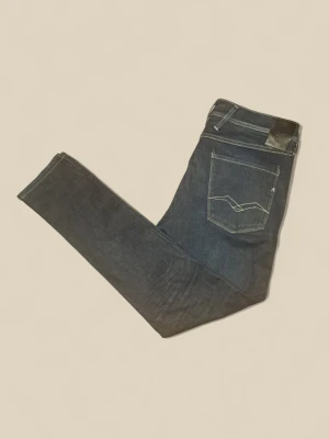 Replay mörkblå jeans slim fit - Snygga mörkblå jeans från Replay med klassisk femficksdesign och kontrastsömmar. Modellen har en slim passform och raka ben, med läderpatch bak i midjan. Perfekta för dig som gillar stilrena och tidlösa jeans. Nypris: 1899. Mitt pris : 399. Man ser färgen lite bättre på andra bilden