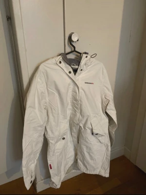 Vit Jacka - Fin jacka från Didriksons, bak på ryggen i backens finns en svag mörk fläck (se sista bilden) men ingenting som stör då luvan täcker den när den är nere🥰 Mått:  Längd (rygg) 85cm Armhåla-Armhåla 52cm Ärmlängd 64cm  Kolla gärna in min profil då jag säljer massor av kläder superbilligt! Tveka inte att höra av dig om du har frågor💕