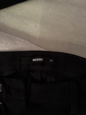 Kostymbyxor svarta  - Säljer ett par svarta bootcut-byxor från BikBok i storlek 34. Byxorna har en klassisk passform med lätt utsvängda ben och midwaist. Snygga till både sneakers och boots, och materialet känns mjukt och följsamt mot kroppen.
