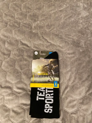 Svarta fotbollsstrumpor Size 40-42 - Svarta fotbollsstrumpor från Seger med vit text 'TEAM SPORT'. Perfekta för dig som vill ha sportiga och bekväma strumpor till match eller träning. Klassisk look och bra passform. ( två olika strumpor ena från seger och andra från team sportia) 