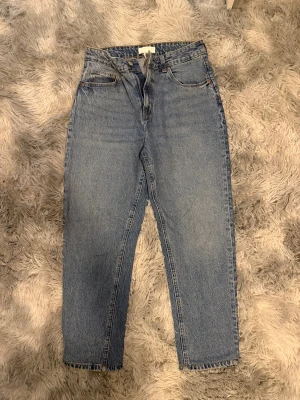 Blå raka jeans i hög midja, strl 40 - Klassiska blå jeans med hög midja och raka ben från H&M. Jeansen har fickor, bälteshällor och stängs med dragkedja och knapp. Perfekt basic i garderoben och passar till allt. 