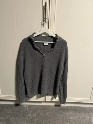Grå stickad tröja  - Liten i storleken passar xs/s! Säljer en grå stickad tröja från Grunt i storlek L. Tröjan har en ribbad struktur och en praktisk half zip-dragkedja vid halsen. perfekt för dig som gillar chill och enkel stil. Skick 9/10 säljs för 450kr pris kan diskuteras!