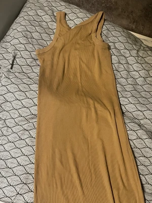Beige ribbad långklänning 157 XS - Säljer en beige ribbad långklänning från 157 i storlek XS. Klänningen är ärmlös med rund hals och har en slim passform som sitter snyggt mot kroppen. Tillverkad i mjuk bomull som känns skön mot huden. Perfekt för dig som gillar enkel och stilren design.