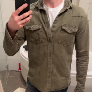 Olivgrön overshirt - Olivgrön overshirt med slitna detaljer säljes, storlek M. Hör av er ifall ni har frågor.             Mvh Erik