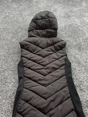 Svart quiltad dunväst från Zara XS - Svart dunväst från Zara i storlek XS. Den sitter fint i midjan men är samtidigt ganska tjock vilket värmen än. Välanvänd men i bra skick!