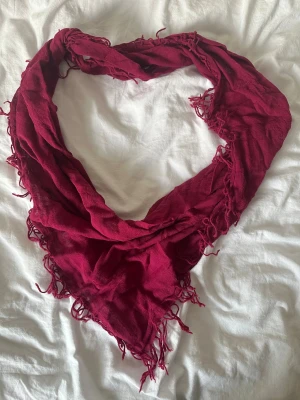 Vinröd tunn halsduk med fransar - Snygg vinröd halsduk i lätt och luftigt tyg, perfekt att slänga över axlarna. Den har en trekantig form och fransar längs kanterna som ger en chill vibe. Materialet är tunt och genomskinligt, vilket gör den enkel att styla på olika sätt