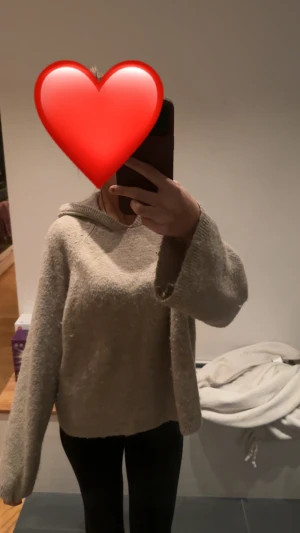 Beige stickad hoodie med huva - Mysig beige stickad hoodie med huva och långärmad design. Tröjan har en loose passform och är perfekt för dig som gillar chill och avslappnad stil. Materialet är mjukt och ger en skön känsla, perfekt för kyliga dagar.