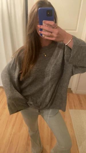 Grå oversized stickad tröja - Mysig grå stickad tröja med oversized passform och långa ärmar. Perfekt för lager-på-lager och chill dagar. Tröjan har en enkel design utan synliga detaljer och är lätt att matcha med jeans eller kjol.