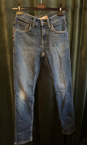 Levi's 512 Slim Taper jeans blå - Snygga Levi's 512 Slim Taper jeans i klassisk blå tvätt med gul kontrastsöm. Modellen har fem fickor, smal passform och avsmalnande ben. Ikonisk Levi's patch bak och röd etikett på bakfickan. Perfekt för dig som gillar en modern och stilren look. Str runt 164cm. Knappt använda och i väldigt bra skick. Pris 299, kan diskuteras. Nypris runt 600kr