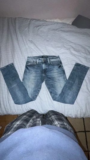 Blå jeans från Mavi Jeans - Snygga blå jeans från Mavi Jeans med klassisk femficksdesign och ljus tvätt. Jeansen har raka ben och normal passform, med detaljer som bruna läderpatch bak i midjan och slitningar för en cool look. Perfekt för dig som gillar stilrena och bekväma jeans. Storlek 28/30!! 