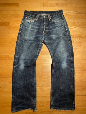 Iron Heart Selvedge jeans straight - Säljer ett par klassiska Iron Heart Selvedge jeans i mörkblå tvätt med slitningar och råa kanter. Modellen har rak passform, fyra fickor och knappgylf. Jeansen är tillverkade i 21oz extra tungt denim med snygga kontrastsömmar och detaljer.                                                                Midja: 38cm                                                                     Lår: 29cm                                                                       Längd: 96cm