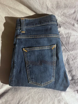 Mörkblå jeans Nudie Jeans, W28 L32 grim Tim - Snygga mörkblå jeans från Nudie Jeans. Grim Tim slim modell Waist 28 Length 32. Mycket bra skick inga defekter och inte urtvättade. Mörk blå