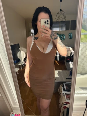 Klänning från Rebecca Stella - Stretchig och figurnära klänning med tunna axelband och låg rygg. Färgen är mörkbeige/brun, nästan guldaktig. ✨ Rebecca Stella