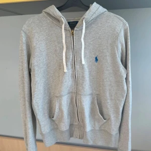Grå hoodie från Polo Ralph Lauren - Säljer en Ralph Lauren Zipp hoodie i storlek M men skulle säga S är bra 😁, färgen är grå med blå märke, vid frågor är det bara att höras 👍😊