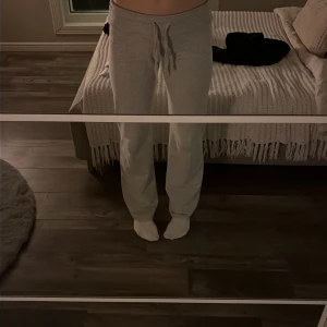Ljusgrå mjukisbyxor/yoga pants från Nelly. - Säljer ett par ljusgrå mjukisbyxor med normal passform och snörning i midjan. Byxorna är raka i modellen.