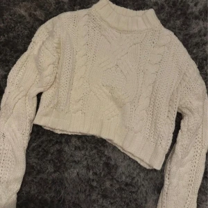 Vit croppad stickad tröja AsYou - Säljer en vit croppad stickad tröja från AsYou i storlek 36. Tröjan har grova flätstickade detaljer framtill, ribbad hals och muddar samt långärmad modell. Perfekt för dig som gillar chunky och mysiga tröjor med lite edge.