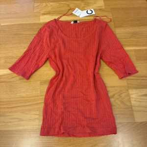 Röd ribbad topp från C, storlek S - Säljer en snygg röd ribbad topp från Cubus i storlek S. Toppen har trekvartsärm och rund halsringning, med ett diskret mönster och croppad passform. Materialet är mjukt och stretchigt, perfekt för dig som gillar färg och enkel stil.