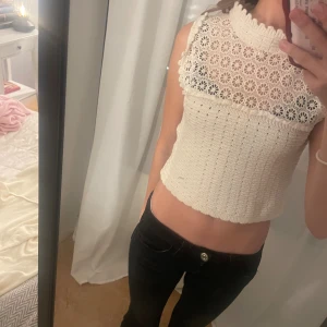Vit spets - Superfin croppad topp från Zara i vit stickad kvalitet med spetsdetaljer och blommigt mönster upptill. Hög hals med volangkant och ärmlös design. Blommig spets både fram och bak, knäppning i nacken.