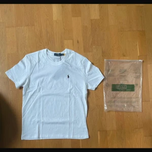 Vit t-shirt från Polo Ralph Lauren - Vit t-shirt från Polo Ralph Lauren i klassisk design med rund hals och korta ärmar. T-shirten har den ikoniska lilla Polo-loggan broderad på bröstet och är tillverkad i mjuk bomull för skön komfort. Perfekt basic-plagg med snygg passform.