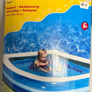 Badpool 200 x 148 x 45 cm - Uppblåsbar badpool från Biltema, mått 200 x 148 x 45 cm. Passar barn från 3 år och uppåt. Poolen har en fräsch blå design och ser ut att vara i gott skick, perfekt för sommarens lek och svalka i trädgården.