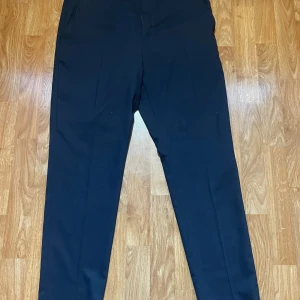 Mörkblå kostymbyxor från Selected Homme - Snygga mörkblå kostymbyxor från Selected Homme med klassisk rak passform. Byxorna har två fickor fram och två bakfickor med knapp. Tillverkade i polyester och viskos för en mjuk och stilren känsla. Perfekta för en clean och dressad look. Köptes för 1 000 kr