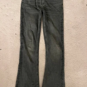 Grå bootcut jeans med utsvängda ben - Säljer ett par grå jeans med bootcut-modell och utsvängda ben. Jeansen har klassisk femficksdesign och är tillverkade i ett mjukt jeanstyg. Perfekta för dig som gillar en retro vibe och vill ha en snygg siluett.