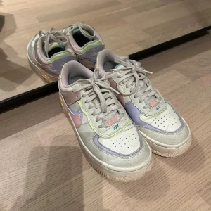 Nike Air Force 1 Pastell sneakers - Nike Air Force 1 sneakers i en snygg mix av pastellfärger som rosa, lila, mintgrön och vitt. Skorna har klassisk snörning, platt sula och rund tå. Perfekt för dig som gillar färg och streetstyle. Skorna är skonsamt använda, köpta för 1445kr på Zalando. 