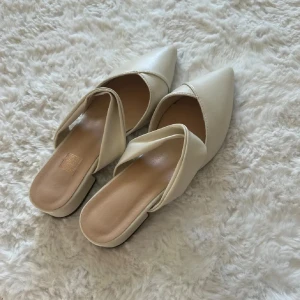 Beige slip-in skor med spetsig tå - Säljer ett par enkla beige skor. Skorna har spetsig tå, låg klack och en snygg omlott-detalj över foten. Dom är 38 men passar 39 oxå💕