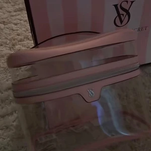 Rosa transparent necessär från Victoria's Secret - Snygg och praktisk necessär från Victoria's Secret i rosa med transparent kropp och silverfärgad dragkedja. Perfekt för att hålla koll på dina småsaker. VS-logga framtill och stilren design. Köpte den från Victoria secret för 800