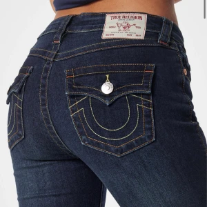 True Religion mörkblå bootcut jeans i mid waist - Snygga mörkblå jeans från True Religion med klassiska kontrastsömmar och ikoniska fickdetaljer med silverknapp. Modellen har bootcut-ben och mid midja, tillverkade i stretchigt jeansmaterial för en skön passform.  Kan tänka mig sänka priset!!!❤️