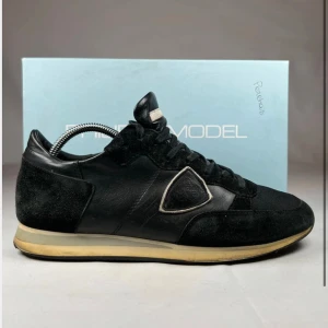  Philippe Model TRPX - Svarta sneakers från Philippe Model med coola detaljer i mocka och skinn. Snyggt broderad logga på sidan och klassisk snörning. Platt sula med vintage-inspirerad gul kant. Perfekt för dig som gillar stilrena och sportiga skor. Orginal Box ingår. Pris kan alltid diskuteras! //By, Olssén, Closet