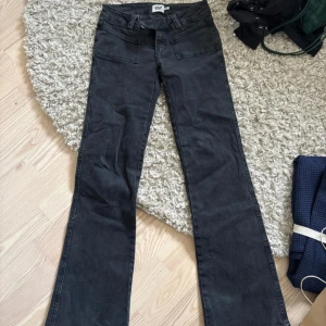 Svarta bootcut jeans från 157 - Snygga svarta jeans från 157 med bootcut passform och klassiska fickor fram. Jeansen har låg midja och är tillverkade i mjukt denimtyg som sitter skönt. Perfekta för dig som gillar en retro vibe och vill ha ett par jeans med lite utsvängda ben.