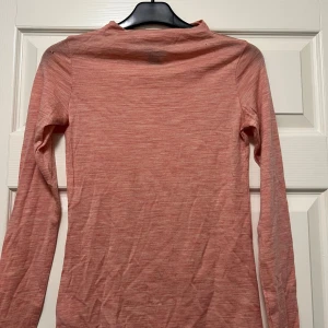 Rosa polotröja från Lindex - En tunn och mjuk rosa polotröja från Lindex med lång ärm. Tröjan har en lätt melerad look och är tillverkad i merinoull . Perfekt för lager-på-lager och passar till både jeans och kjol. Tyvärr har den 3-4 hål i tyget, därav priset.