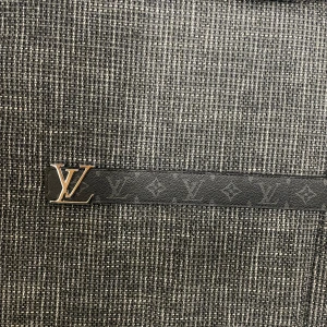 Louis Vuitton svart monogram bälte - Säljer ett svart Louis Vuitton bälte i skinn med klassiskt monogrammönster och en snygg LV-logga i metall som spänne. Bältet är stilrent och passar perfekt till jeans eller kostymbyxor. Märkt med 'Louis Vuitton Paris' och tillverkat i Spanien.
