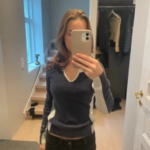 Mörkblå v-ringad tröja💕💕 - Snygg mörkblå stickad tröja med v-ringning och kontrasterande vita detaljer vid hals, sidor och ärmar. Tröjan har lång ärm och en slim passform som sitter riktigt bra. Perfekt för dig som gillar klassisk stil med en modern twist.