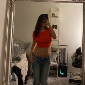 Orange croppad topp från Monki - Säljer en snygg orange croppad topp från Monki i ribbad bomull. T-shirten har rund halsringning och korta ärmar, perfekt för dig som gillar färg och vill ha en enkel men trendig look. Passar dig som vill ha en tight passform och gillar att sticka ut. Storleken är M känns som S 