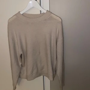 Vit stickad tröja med rund hals - En enkel och stilren vit stickad tröja med rund hals och långa ärmar. Perfekt för att hålla sig varm under kyliga dagar. Tröjan har en mjuk och skön känsla och passar till många olika outfits.